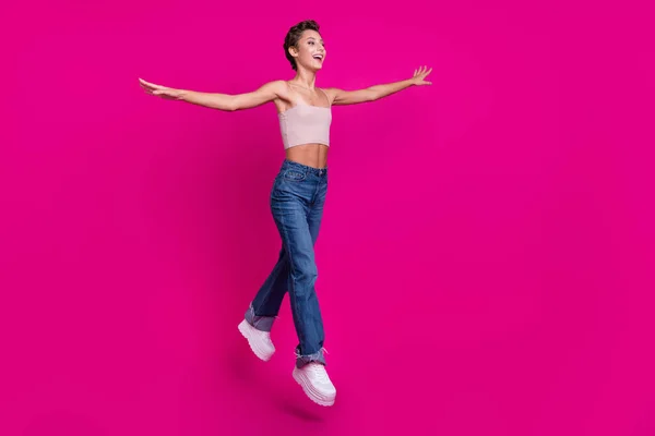 Pełne ciało zdjęcie pozytywnej aktywnej młodej kobiety hipster podnieść ręce płaskie skrzydła cieszyć się izolowane na tle koloru magenta — Zdjęcie stockowe