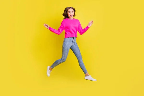Full längd foto av söt bedårande vågig ung kvinna bära rosa tröja hoppa gå isolerad gul färg bakgrund — Stockfoto