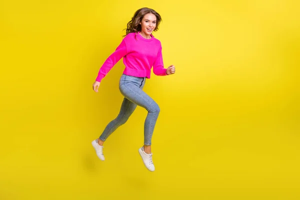 Volledige lengte foto van schattige doelgerichte golvende jonge vrouw dragen roze trui springen lopen geïsoleerde gele kleur achtergrond — Stockfoto