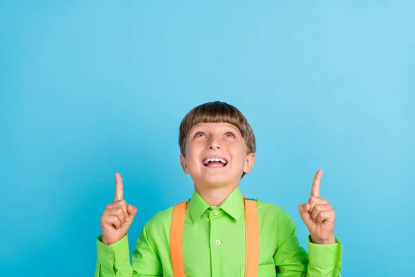 흥분 한 어린 소년 이 푸른 색 배경에 고립된 빈 공간을 손가락으로 가리키는 긍정적 인 놀란 사진 — 스톡 사진