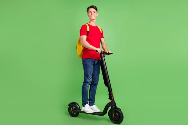 Foto in voller Länge von jungen Kerl glücklich positives Lächeln Fahrt Elektroroller Reise isoliert über grüne Farbe Hintergrund — Stockfoto