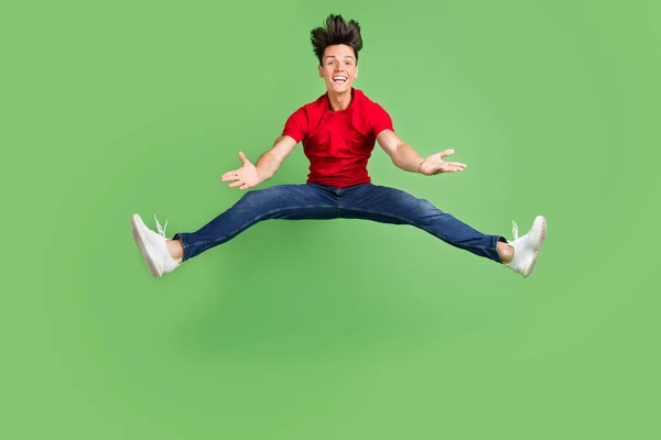 Photo d'un jeune homme assez impressionné habillé en t-shirt rouge sautant haut sourire isolé fond de couleur verte — Photo