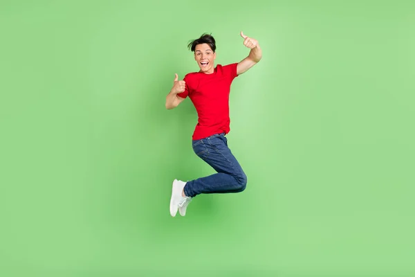Pełne ciało zdjęcie młodego faceta szczęśliwy uśmiech skok pokazać kciuk do góry jak wybór grzywny opinie izolowane nad zielonym tle koloru — Zdjęcie stockowe