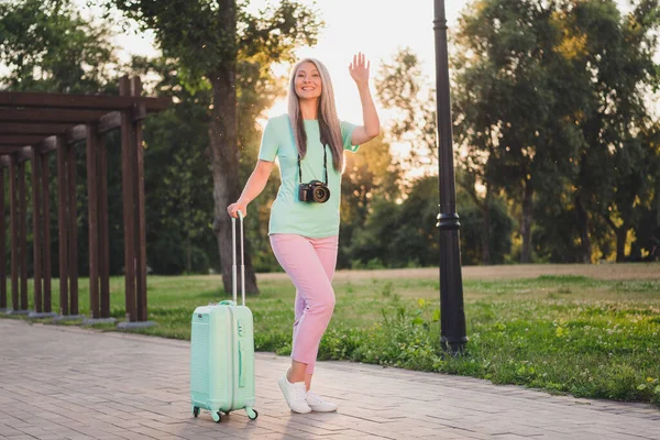 Vista completa del tamaño del cuerpo de la atractiva mujer alegre de pelo gris que lleva la aventura del bolso saludando hola al aire libre — Foto de Stock