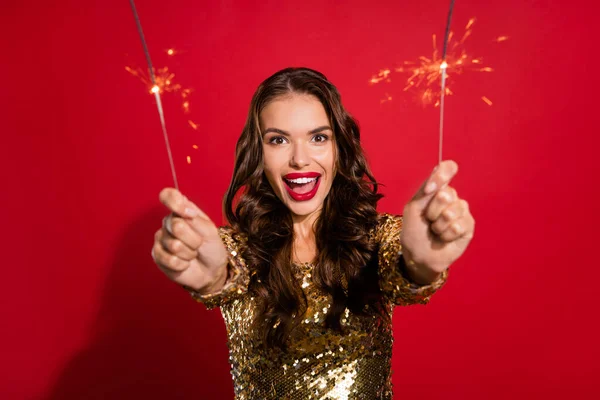 Photo of crazy excited lady hold two sparkling fire sticks wear golden dress isolated red color background