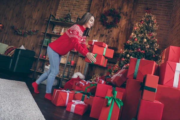 Kırmızı kazaklı, sevimli genç bir kadının fotoğrafı. Yeni yıl ağacının altına hediyeler koyuyor. Evin içinde gülümsüyor. — Stok fotoğraf