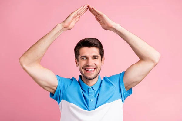 Foto von jungen lächelnden Mann halten Hände Dachform sicher bewegen neue Wohnung isoliert auf pastellfarbenem Hintergrund — Stockfoto