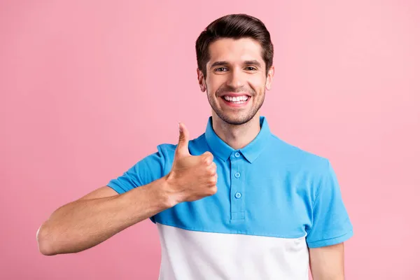 Photo de brunet drôle jeune homme montrer pouce vers le haut porter t-shirt bleu isolé sur fond de couleur rose — Photo