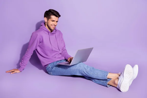 보라색 배경 위에 따로 떨어져서 수업을 보고 노트북을 사용하여 앉아 있는 매력적 인 쾌활 한 남자의 그림 — 스톡 사진