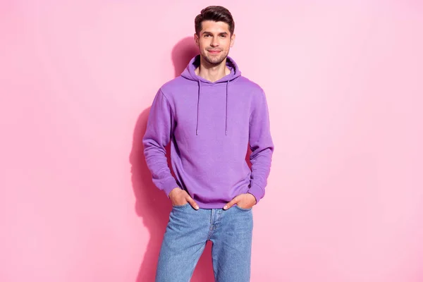 Portret van aantrekkelijke vrolijke content guy het dragen van comfortabele hoody hand in hand in zakken geïsoleerd over roze pastel kleur achtergrond — Stockfoto