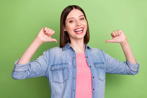 Foto de cabelo morena legal millennial senhora apontar-se usar jaqueta jeans isolado no fundo de cor verde — Fotografia de Stock