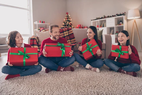 Fotografie legrační pěkný táta maminka dvě děti oblečené červené svetry dostat nový rok dárky s úsměvem vnitřní pokoj domácí dům — Stock fotografie