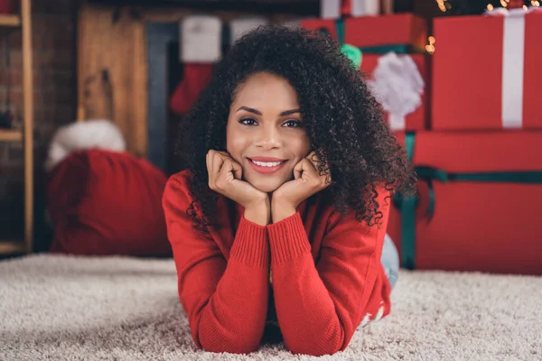 Foto av ung afro kvinna glad positiv leende händer beröring kinder dröm liggande golv vila semester nytt år inomhus — Stockfoto