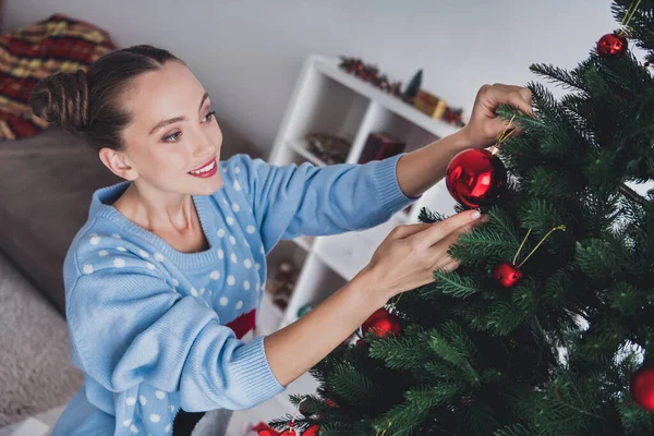 Neşeli, genç ve mutlu bir kadının fotoğrafı oyuncaklar asar Noel ağacı, oturma odasındaki dairede kutlanır. — Stok fotoğraf