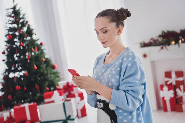 Фото серйозної молодої жінки тримає руки телефон читати повідомлення Різдво гарний настрій всередині будинку — стокове фото