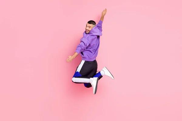 Full size profiel foto van grappig millennial brunet guy springen dragen hoodie broek schoenen geïsoleerd op roze achtergrond — Stockfoto
