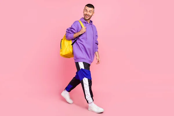 Full length φωτογραφία του funky νεαρός brunet τύπος πάει να φορέσει κουκούλα παντελόνι παπούτσια τσάντα απομονώνονται σε ροζ φόντο — Φωτογραφία Αρχείου