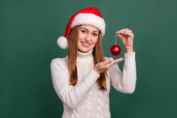 Portret van aantrekkelijke vrolijke vrouw houden in de hand bal avond nieuwjaar verrassing geïsoleerd over groene kleur achtergrond — Stockfoto