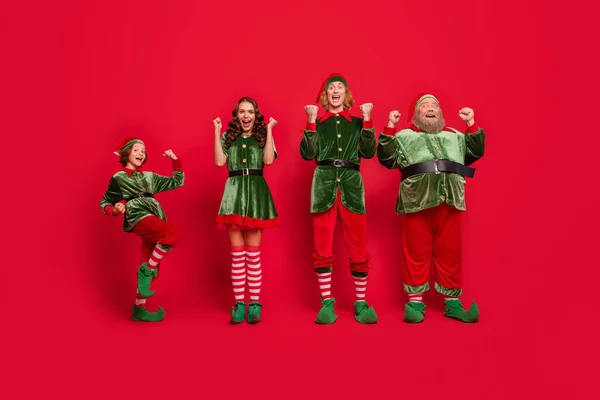 Full längd foto av fira Santa team händer nävar bära nya år kostymer isolerad på röd färg bakgrund — Stockfoto
