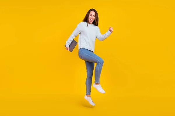 Foto de longitud completa de feliz dama alegre celebrar ganador de salto portátil buen humor aislado en el fondo de color amarillo — Foto de Stock
