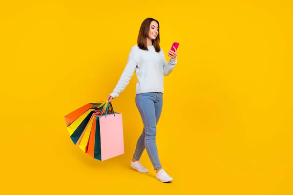 Pleine photo du corps des cheveux bruns élégant mode femme marcher boutique sac tenir téléphone isolé sur fond de couleur jaune — Photo