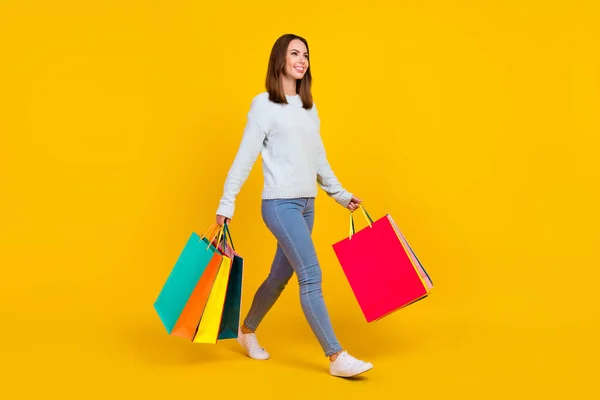 Pełnowymiarowe zdjęcie miłej młodej kobiety trzymać wiele toreb na zakupy wyglądają puste miejsce spacer izolowany na żółtym tle kolor — Zdjęcie stockowe