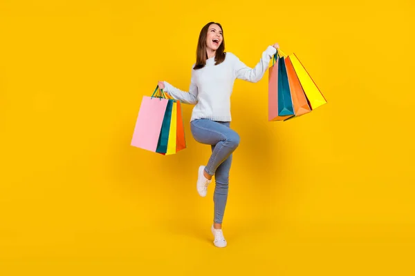 Volledige lengte foto van gelukkige jonge vrouw houd handtassen kijken lege ruimte win verkoop geïsoleerd op gele kleur achtergrond — Stockfoto