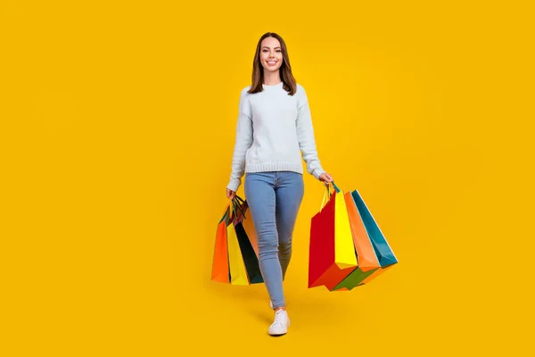 Mutlu genç kadının tam boy fotoğrafı el ele tutuşurken alışveriş merkezinin gülümsemesi sarı arka planda izole edilmiş. — Stok fotoğraf