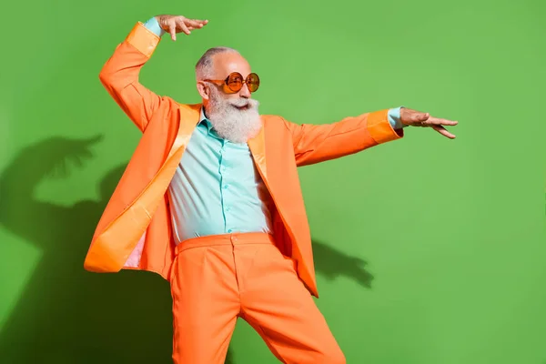 Портрет привлекательного комического веселого седого мужчины, танцующего, веселящего, изолированного на ярко-зеленом фоне — стоковое фото
