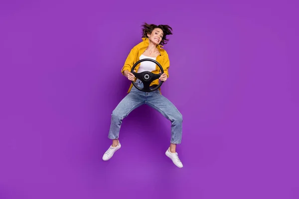 Plná délka tělo velikost pohled atraktivní zmatená dívka skákání držení volantu izolované přes světlé fialové barvy pozadí — Stock fotografie