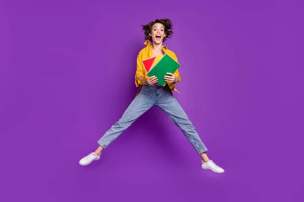 Longitud completa vista del tamaño del cuerpo de la atractiva chica alegre sorprendido saltar celebración libro aislado sobre violeta brillante color púrpura fondo —  Fotos de Stock