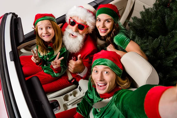 Foto di abbastanza carino Babbo Natale assistenti di guida auto che mostra v-segno pollici su isolato sfondo di colore bianco — Foto Stock