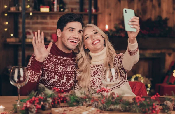 Portret dwóch pięknych, pięknych, wesołych małżonków spędzających festalowy wieczór w wigilię robiąc selfie machając pozdrowieniami w domu — Zdjęcie stockowe