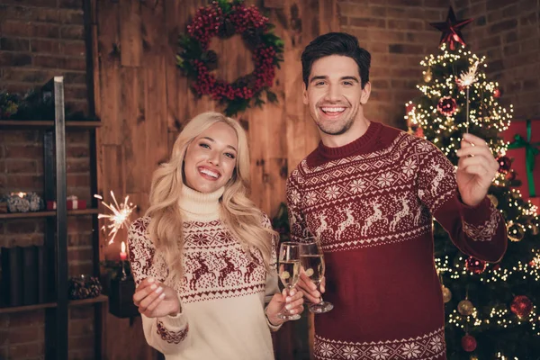 Foto de bonito animado esposa marido usar camisolas de impressão beber champanhe segurando fogos de artifício celebrando noel dentro de casa casa casa quarto — Fotografia de Stock