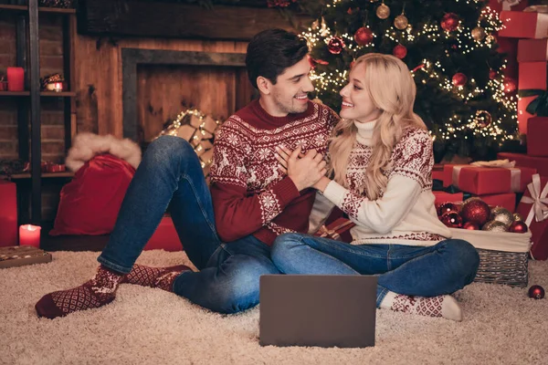 Pełna długość zdjęcie flirciarza para przytulić w pobliżu laptopa siedzieć na dywanie nosić swetry dżinsy skarpetki wewnątrz w Wigilię — Zdjęcie stockowe