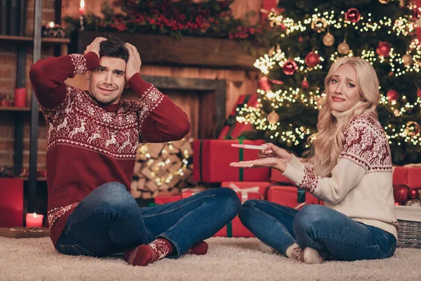 Pełny rozmiar zdjęcie przerażonej pary trzymać test ciążowy nosić czerwony sweter dżinsy skarpety wewnątrz w pobliżu drzewa w Wigilię Bożego Narodzenia — Zdjęcie stockowe