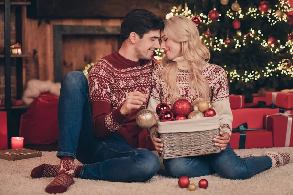 Retrato de dos atractivos cónyuges casados dulces y tiernos sentados en la alfombra decorando abeto nuevo año personalizado en el interior —  Fotos de Stock