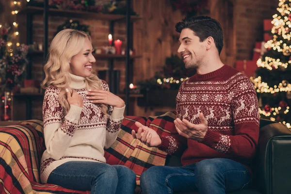Zdjęcie pod wrażeniem podekscytowany żona mąż ubrany pulowerów druku rozmowy korzystających Nowy Rok uśmiechając się w pomieszczeniu domu domu — Zdjęcie stockowe