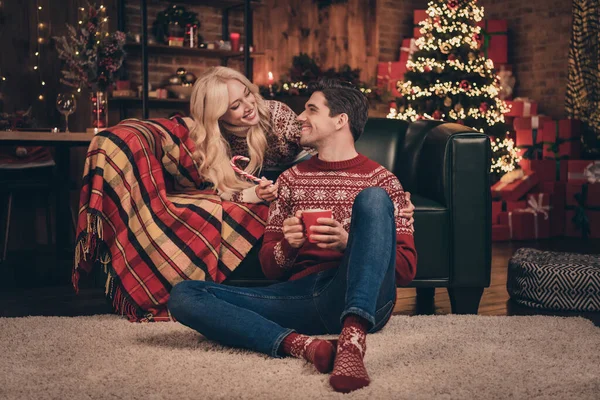 Zdjęcie pozytywne ładny mąż żona nosić druk swetry uśmiechając się pijąc nowy rok napoje wewnątrz domu dom pokój — Zdjęcie stockowe
