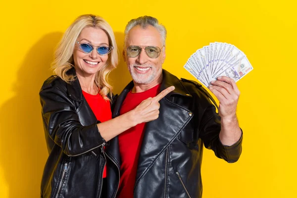 Retrato de pensionista bonito bonito cônjuges alegres demonstrando lucro isolado sobre fundo de cor amarelo brilhante — Fotografia de Stock