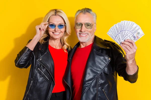 Portret van gepensioneerde mooie knappe vrolijke echtgenoten houden cashback credit bank geïsoleerd over fel gele kleur achtergrond — Stockfoto