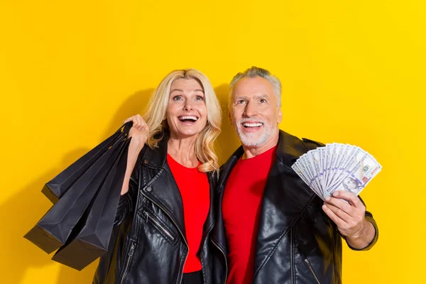 Retrato de pensionista bonito bonito cônjuges alegres comprar roupas cashback banco isolado sobre cor amarela brilhante fundo — Fotografia de Stock