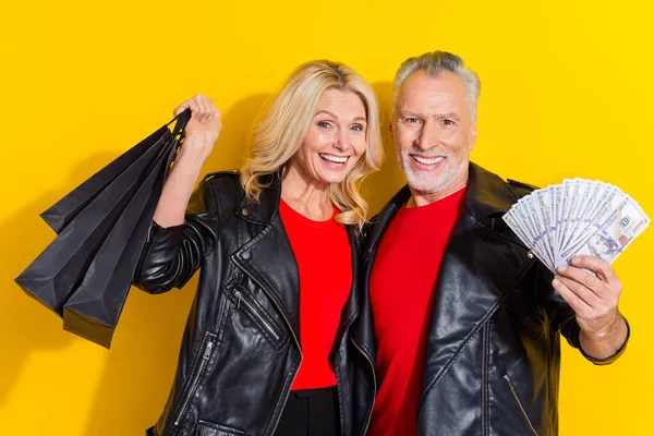 Portret van gepensioneerde mooie knappe vrolijke koele echtgenoten kopen goederen cashback geïsoleerd over helder gele kleur achtergrond — Stockfoto