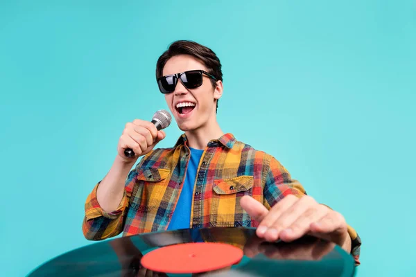 Φωτογραφία από δροσερό αυτοπεποίθηση dj ρετρό τύπος τραγουδούν μικρόφωνο δίσκο βινυλίου χέρι φορούν καρό πουκάμισο απομονωμένο aquamarine φόντο χρώμα — Φωτογραφία Αρχείου