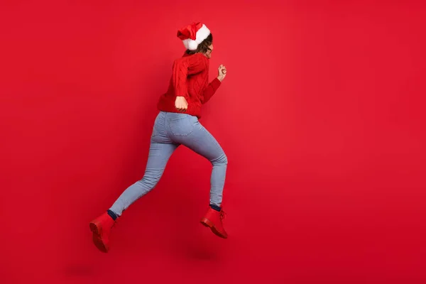 Зворотній перегляд фотографія повного тіла молодої дівчини, що стрибає вгору, біжить швидким новим роком ізольовано на фоні червоного кольору — стокове фото