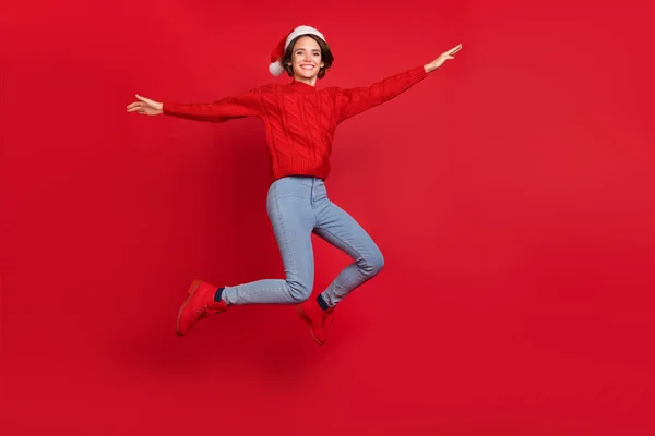 Heyecanlı genç kızın tüm vücudu mutlu bir gülücük atlama Noel 'i kırmızı arka planda izole edilmiş. — Stok fotoğraf