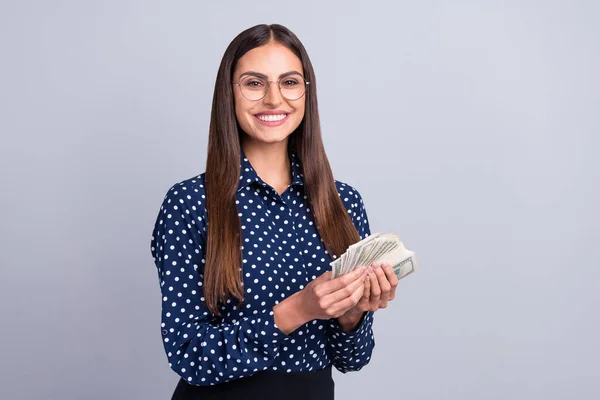 Foto di positivo ricco banchiere signora tenere mucchio contanti dollari indossare occhiali punteggiato camicetta isolato colore grigio sfondo — Foto Stock