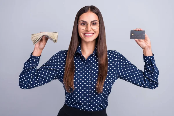 Taraftar parası tutan zeki, neşeli iş kadınının portresi gri arka planda izole edilmiş bir USD banka kartı. — Stok fotoğraf
