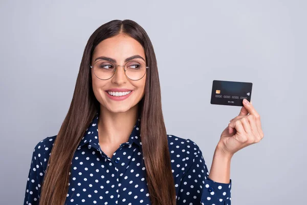 Zdjęcie ciekawski inteligentny bankier pani trzymać karty kredytowe wygląd strony zużycie specs kropkowana bluzka odizolowany szary kolor tła — Zdjęcie stockowe