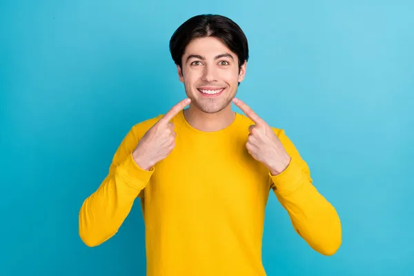 Foto de jovem cara legal ponto sorriso usar camisa amarela isolada no fundo de cor azul — Fotografia de Stock